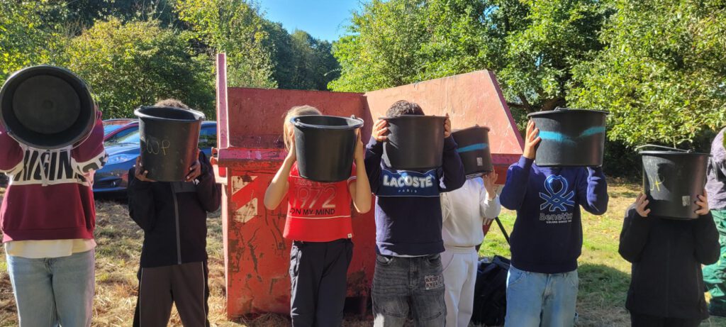 kinder bei der apfelernte streuobstwiese 2627. sie halten eimer vor das gesicht
